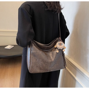 Detail view of large vintage coffee brown tote bag with matte leather and plush charm