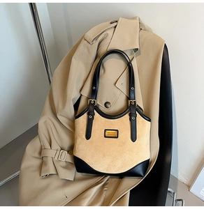 Detail der hellbraunen Wildleder-Achseltasche mit schwarzen Lederriemen und Goldlogo