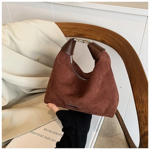 Nahaufnahme einer dunkelbraunen Wildleder-Halbmondtasche mit elegantem Metallgriff