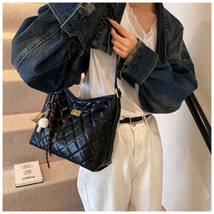 Détail du sac seau noir matelassé avec fermoir doré et pendentif mini baseball