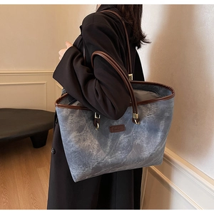 Detail of grey marble textured tote bag featuring dark brown trim and golden hardware