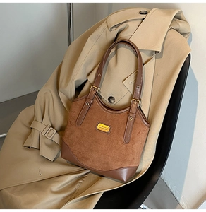Details von Wildleder-Leder-Nähten mit goldener Schnalle an dunkelbrauner Tragetasche