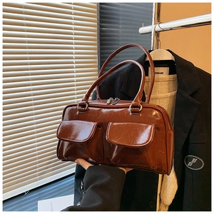 Vue détaillée de la texture en cuir ciré marron et des poches à rabat du sac à main