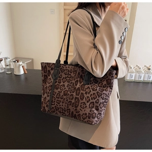 Detailed close-up of large leopard print tote bag with black leather straps and soft suede texture