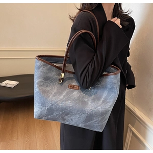Detail of blue marble pattern tote bag with brown leather straps shown on a model