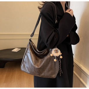 Detail of vintage brown leather tote bag featuring a lion plush charm on side strap