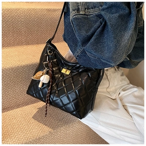 Détail du sac seau en cuir matelassé noir avec fermoir doré et breloque de baseball