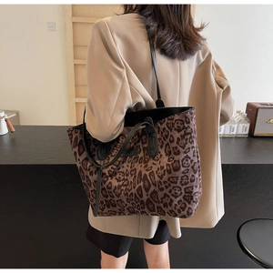 Leopard print tote bag with black leather straps shown in a modern lifestyle setting