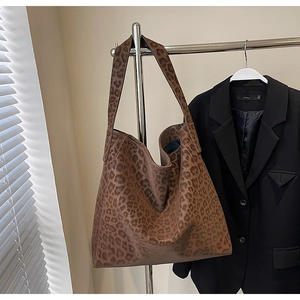 Detailed view of leopard print tote bag hanging on a rack with textured fabric