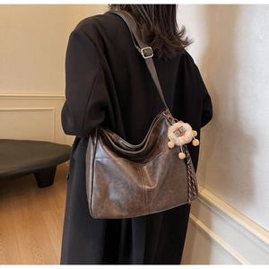 Detail of dark brown vintage faux leather tote with plush lion charm and wide strap