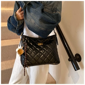 Détail d'un sac bandoulière en cuir noir matelassé avec fermoir tournant doré chic