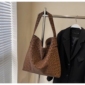 Detailed view of the large leopard print tote bag hanging on a metallic display stand