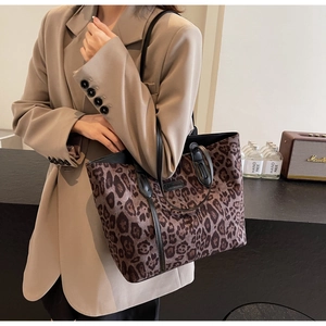 Detailed texture of leopard print tote bag with black leather handle and shoulder strap