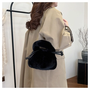 Detailed view of plush black faux fur bucket bag with golden chain strap and drawstring