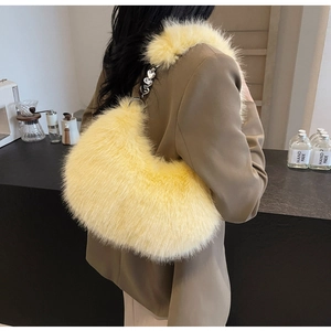 Sac hobo jaune clair en fausse fourrure avec chaîne argentée à cœurs dans un décor de café