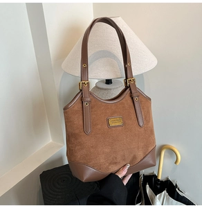 Nahaufnahme der braunen Wildleder-Leder-Nähte mit goldenen Beschlägen an der Tasche