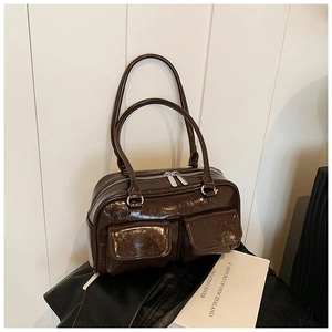 Détail d'un sac à bandoulière en cuir verni marron avec texture brillante et deux poches