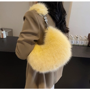 Détail du sac sous le bras en fausse fourrure jaune avec chaîne en métal à cœurs