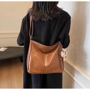 Detail view of large vintage brown faux leather tote bag with stylish pompom bag charm