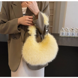 Détail de la texture en fausse fourrure jaune avec chaîne cœur en métal sur le sac