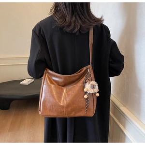 Detailed back view of a large brown vintage leather tote bag on a black wool coat
