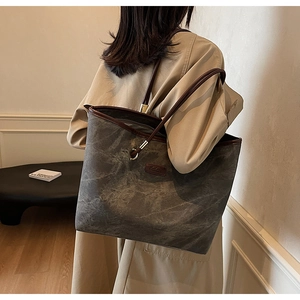 Detailed close-up of high-capacity tote bag with grey canvas and brown leather straps