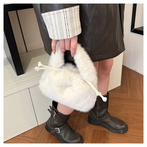 Detail of white faux fur bucket bag featuring plush texture and woven drawstring cords