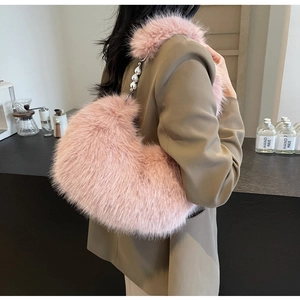 Sac sous le bras en fausse fourrure rose avec bandoulière perlée porté par un modèle