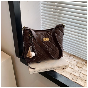 Détail du sac seau matelassé marron avec fermoir doré et pendentif de baseball chic
