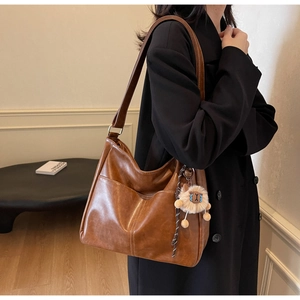 Detail of vintage brown leather tote bag with plush sheep charm for daily commute