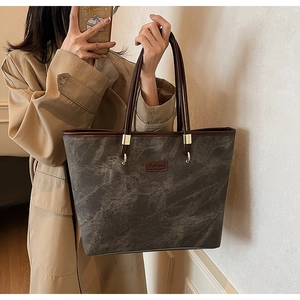 Detailed view of the large tote bag with brown leather trim and a fashion label