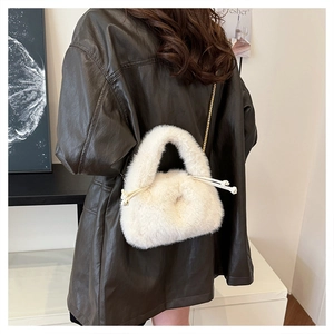 Detail shot of white faux fur bucket bag with golden chain strap on model shoulder