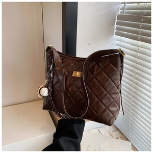 Vue détaillée du sac cabas matelassé marron foncé avec boucle dorée et breloque baseball
