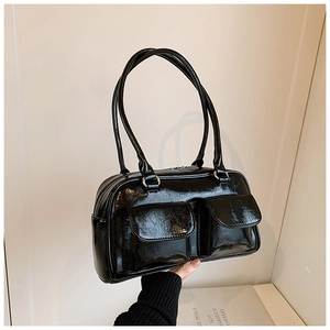 Détail du sac à bandoulière noir brillant avec deux poches avant à rabat et texture cuir