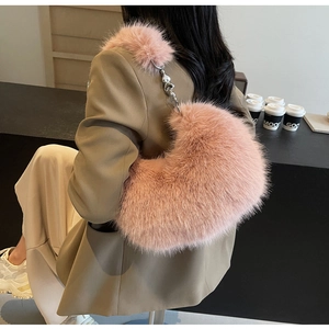 Détail du sac croissant en fausse fourrure rose avec chaîne argentée porté par le modèle