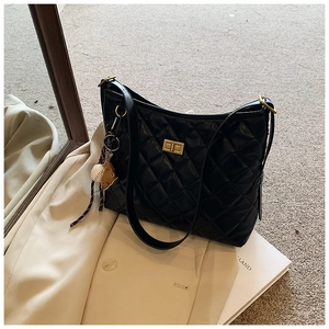 Détail du sac hobo matelassé noir avec fermoir doré sur fond de trench-coat beige