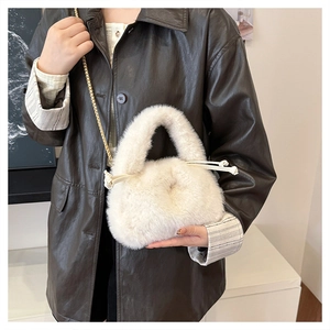 Detail of plush off-white bucket bag with drawstring and golden metal chain strap