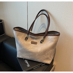 Detail of taupe vintage tote bag with 'Fashion' badge and sturdy brown shoulder straps
