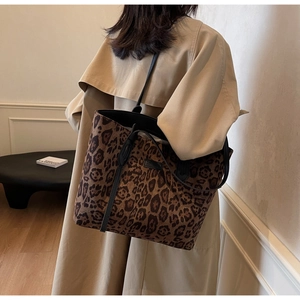 Detailed side view of large leopard print tote bag with black leather shoulder straps