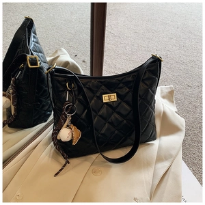 Détail du sac seau noir matelassé avec fermoir doré et charme baseball sur manteau