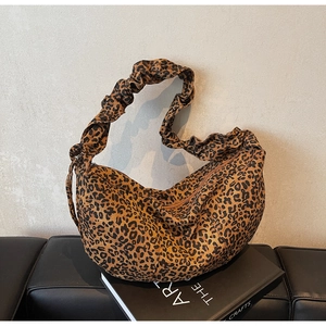 Détail du sac hobo léopard avec bandoulière froncée sur un fond minimaliste chic