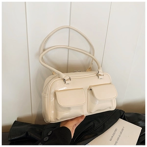 Détail d'un sac à main blanc crème brillant avec double poches à rabat et anses