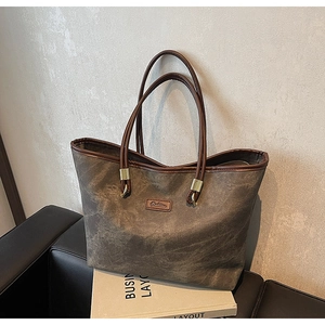 Close-up of vintage canvas tote bag with brown leather handles and golden metal rings