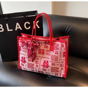 Detail of a festive wedding tote bag with Double Happiness print on a black leather sofa