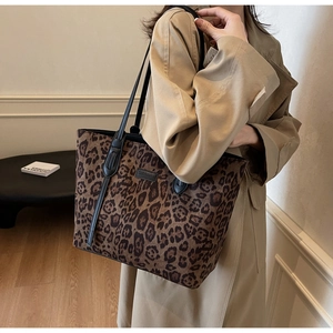 Detail of leopard print tote bag styled with a trench coat showing texture and handles