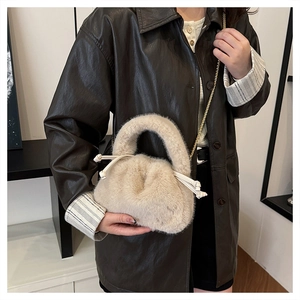 Detail of plush faux fur bucket bag with drawstring closure and golden chain strap