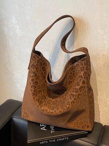 Chic leopard print oversized suede tote bag styled on a luxury black leather chair
