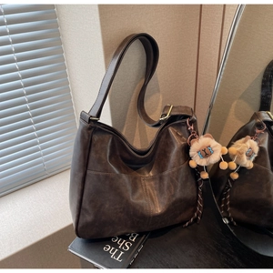 Detail of vintage coffee brown large hobo bag with a plush doll charm on black books