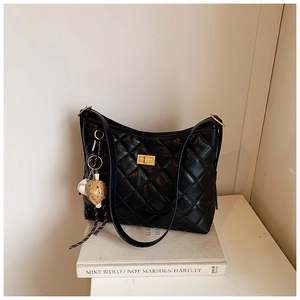 Détail d'un sac seau noir matelassé avec fermoir doré et pendentif de baseball élégant