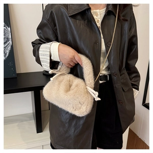 Close-up of beige plush bucket bag with golden chain strap and soft faux fur texture